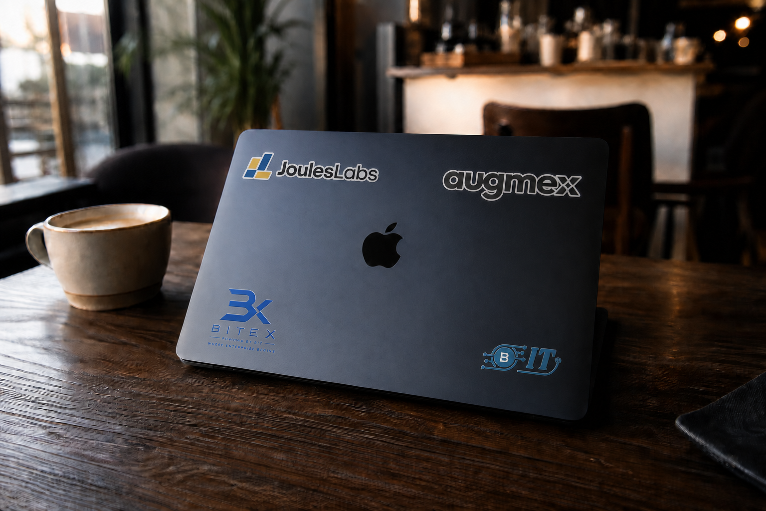 A branded Midnight MacBook on a warm café table beside coffee