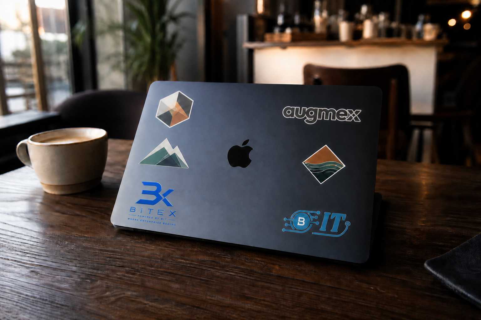 A branded Midnight MacBook on a warm café table beside coffee