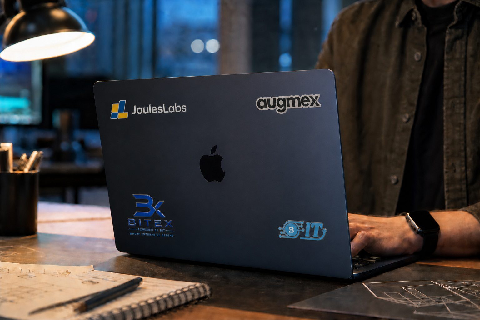 A person working on a branded Midnight MacBook at a design desk